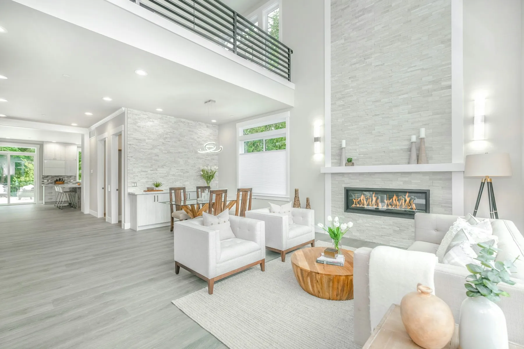A bright double-height living room with a fireplace and pale floors